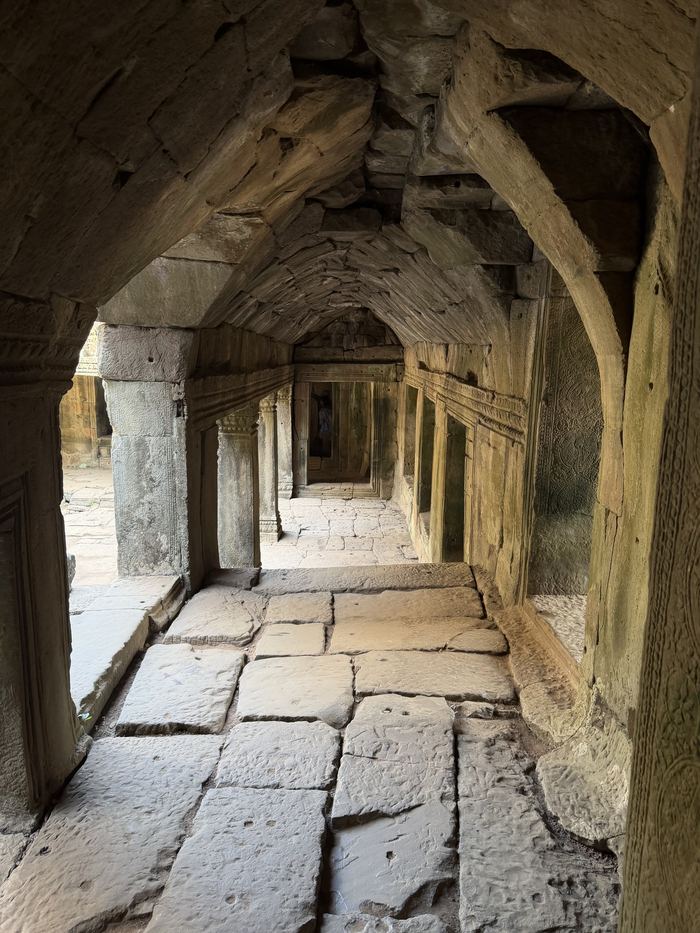 A long stone corridor with carved pillars inside Angkor Wat