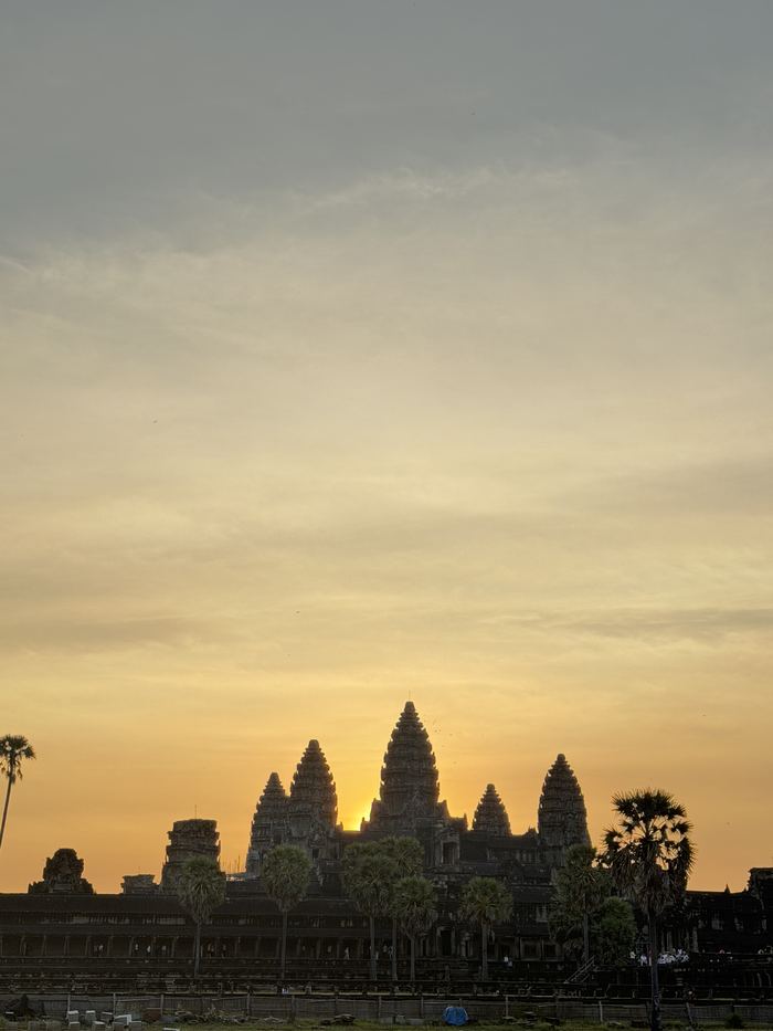 The silhouette of Angkor Wat's towers against an orange sunrise sky