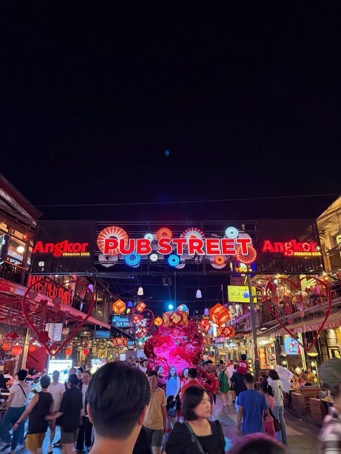 The neon Pub Street sign above a crowded street at night