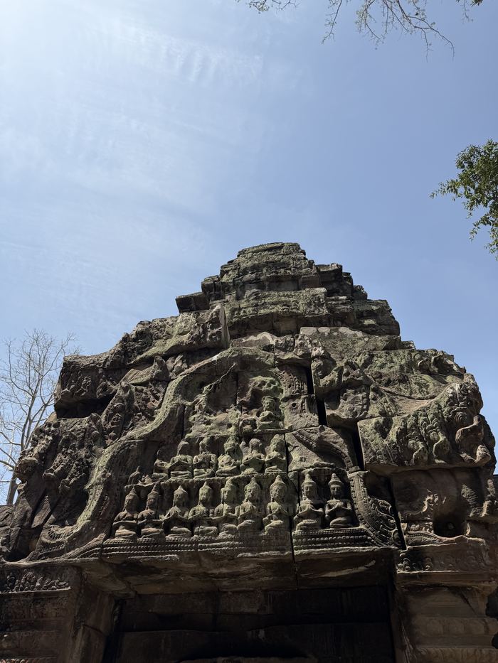 A carved stone tower at Ta Prohm against a blue sky