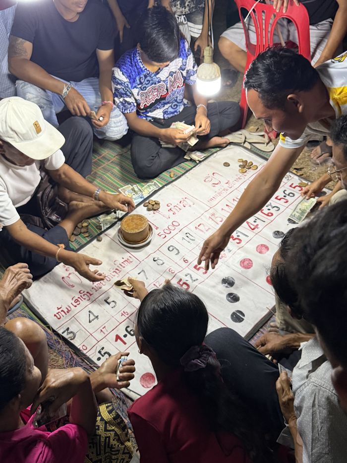 A group of people playing a dice game on a mat