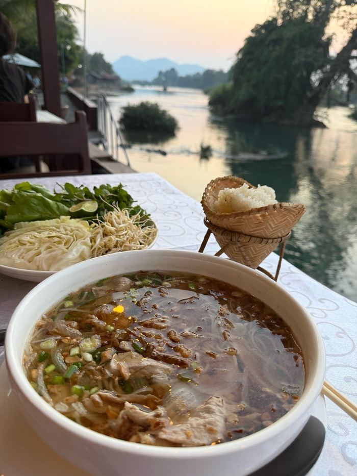 Noodle soup with herbs on a table by the Mekong River