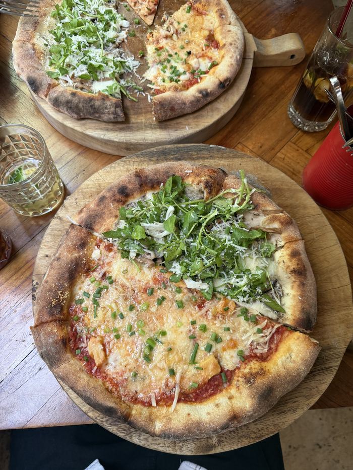 Two wood-fired pizzas on a wooden table