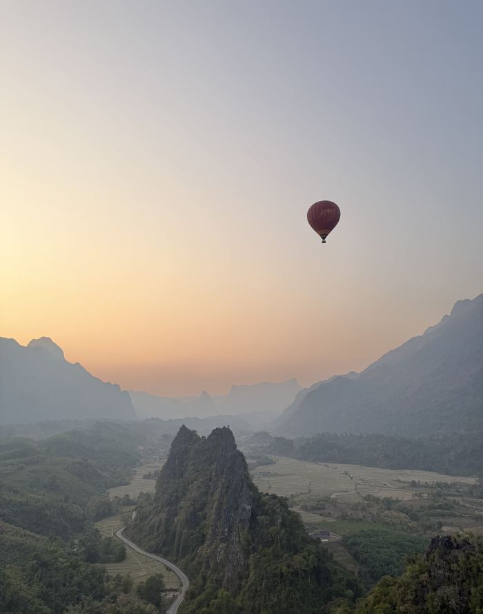 A hot-air balloon over the valley and karst peaks at sunrise
