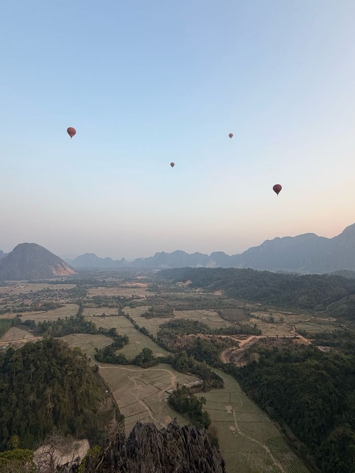 Hot-air balloons over the valley and rice fields of Vang Vieng