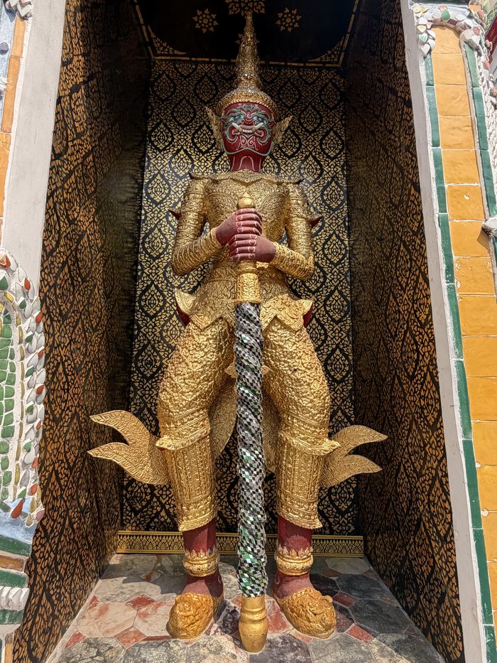 A golden giant guardian statue in a temple alcove
