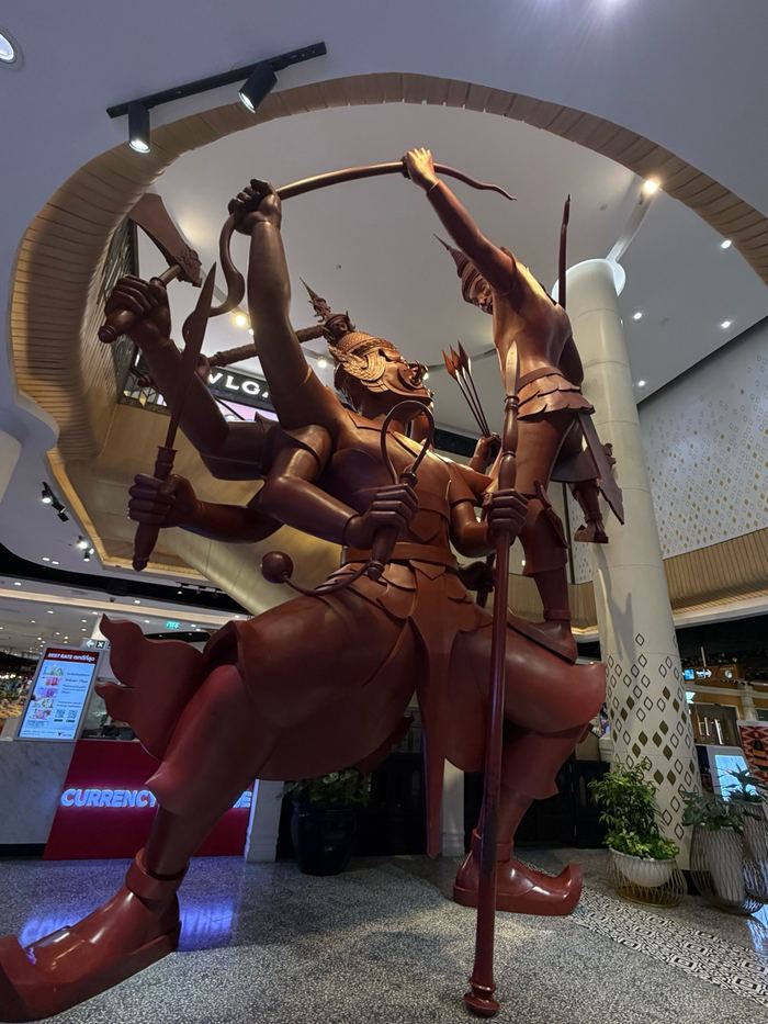 A large multi-armed wooden statue inside a mall
