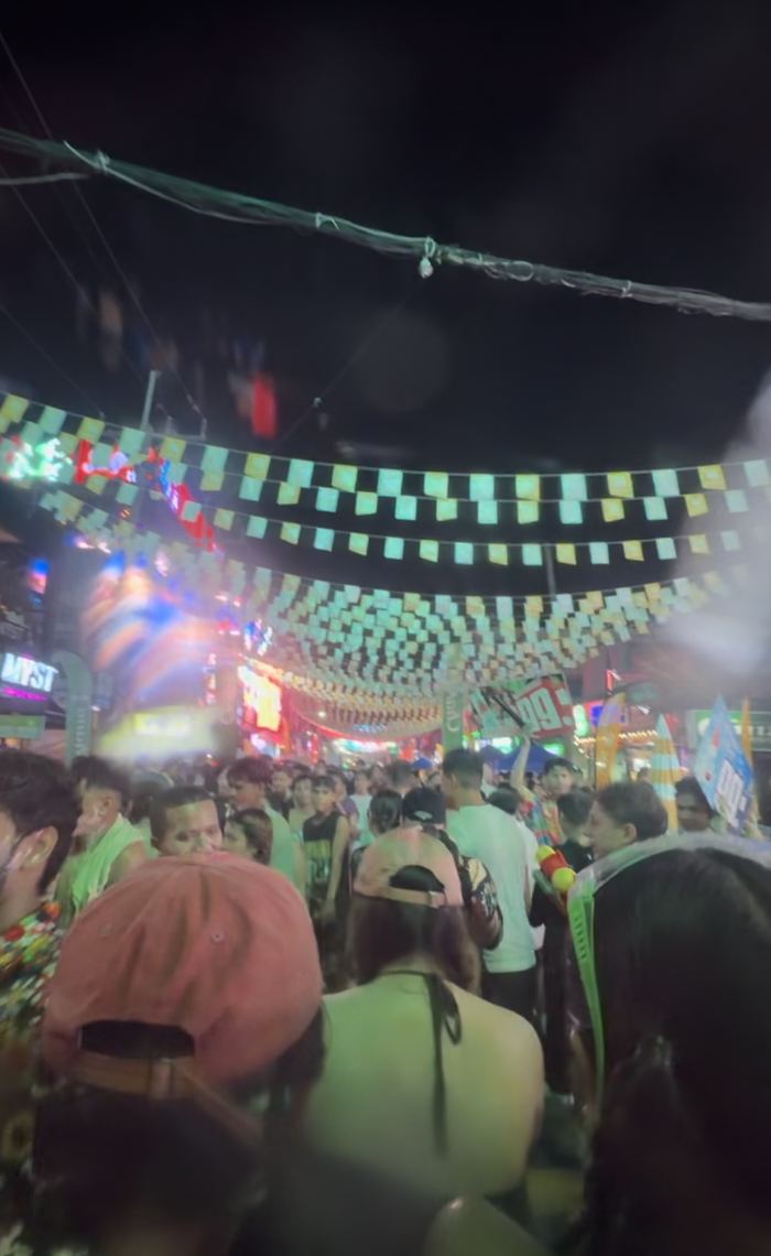 A crowd walking under flag bunting during Songkran