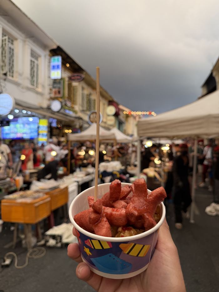 A cup of sausages at a busy street market
