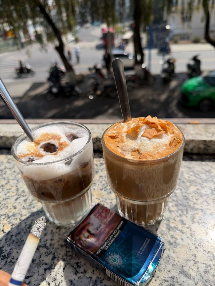 Two iced coffees and cigarettes on a ledge above the street