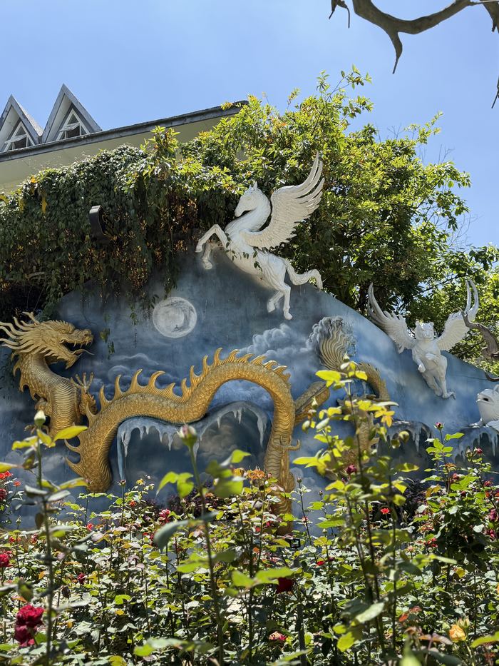 A dragon and pegasus sculpture above a rose garden