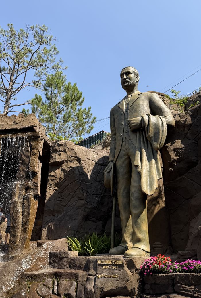 A bronze statue of a man in a suit beside a rock waterfall