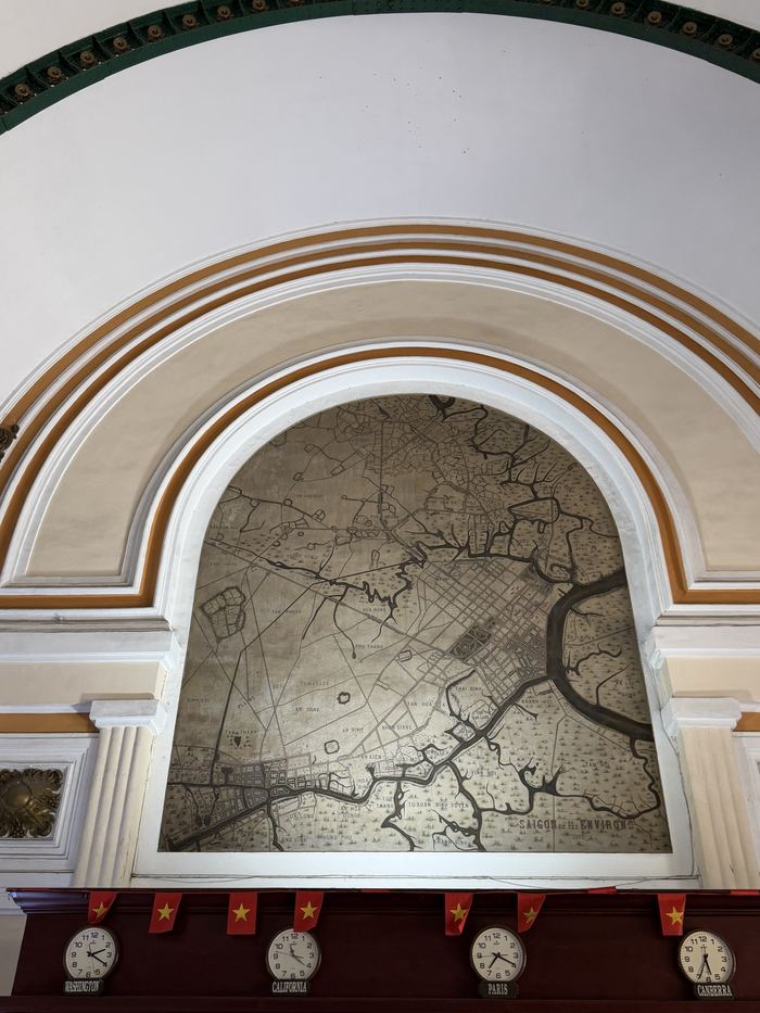 An old painted map in an arch above a row of clocks