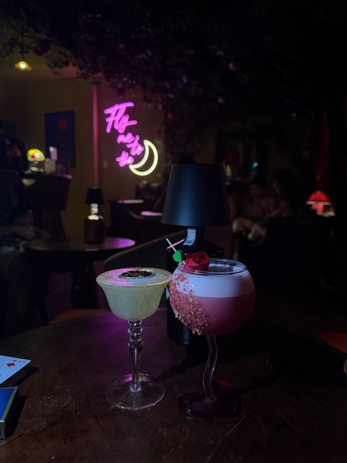 Two cocktails in a dark bar with neon signs
