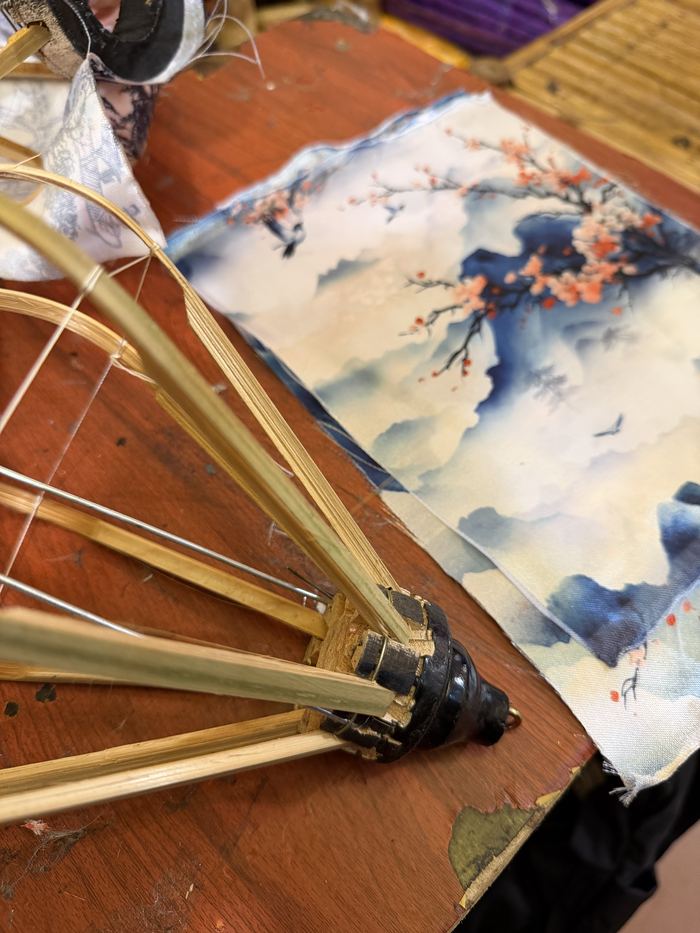 A bamboo lantern frame and painted silk on a work table