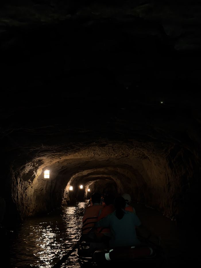 Boats passing through a dark, low cave