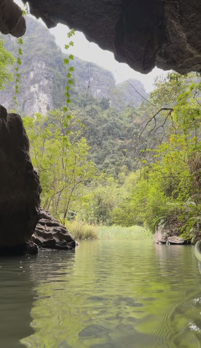 Looking out of a cave mouth onto green water and cliffs