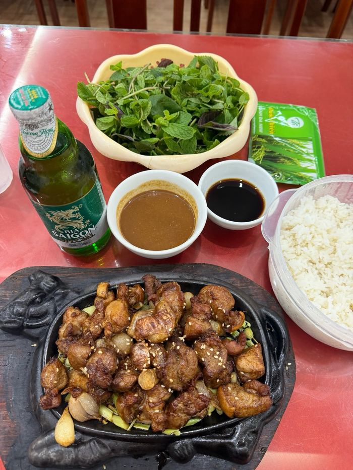Sizzling goat with dipping sauces, herbs, and a beer