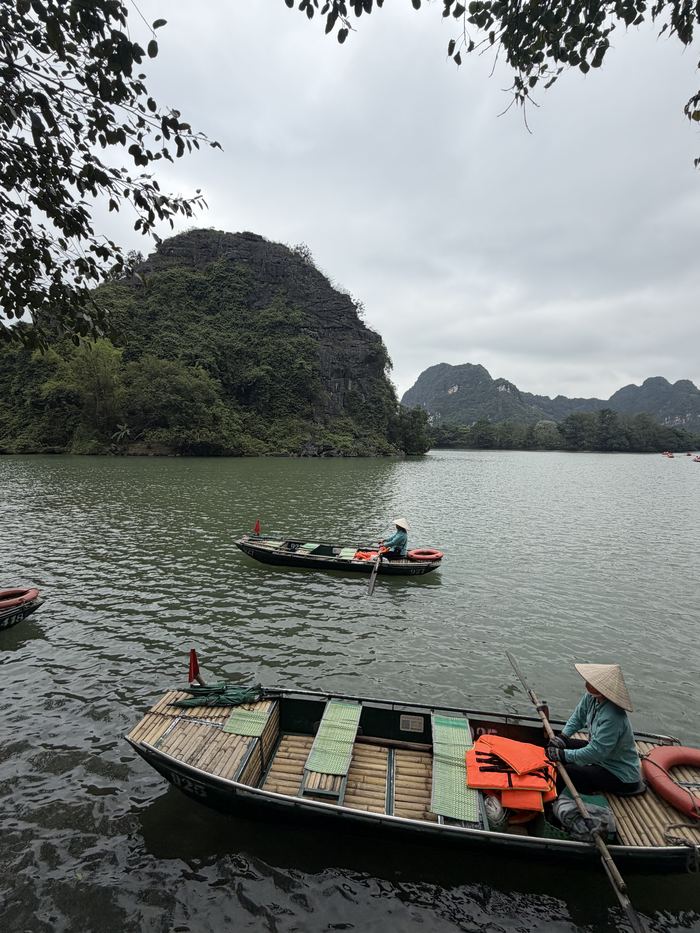 Rowers in conical hats on the river between karst mountains