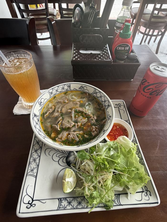 Noodle soup with herbs, an iced tea, and a Coke