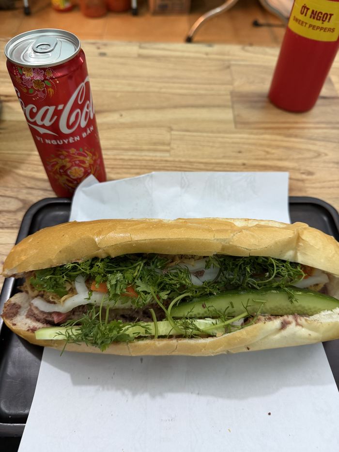 A banh mi next to a can of Coca-Cola