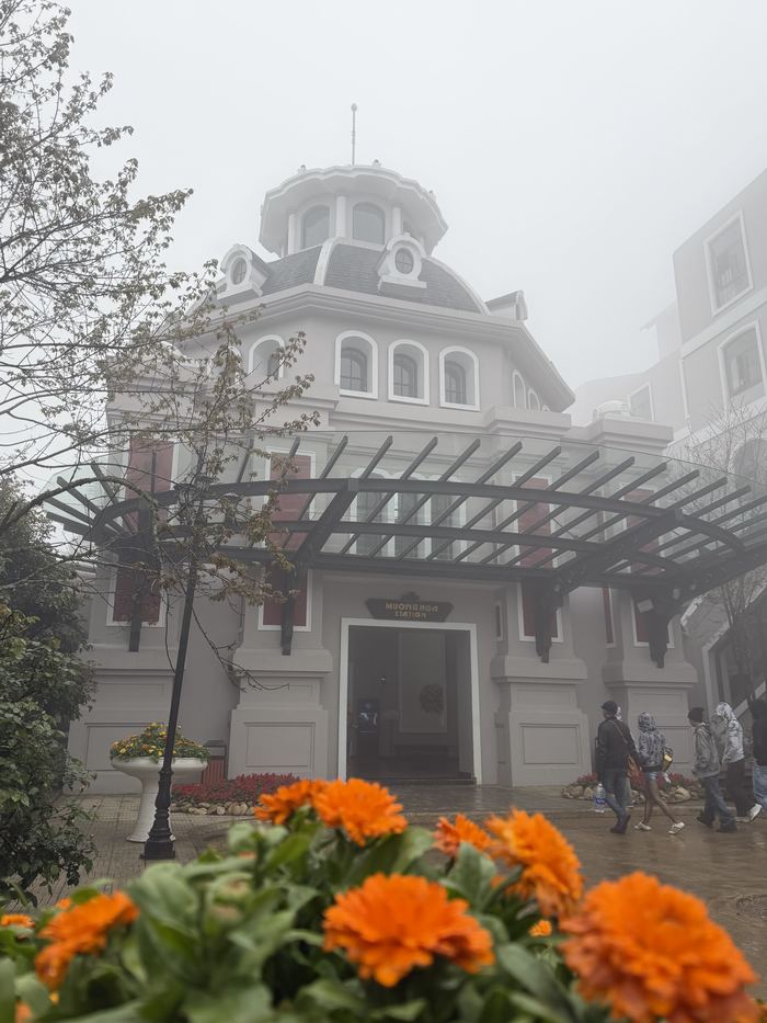 A white colonial-style building with orange flowers in front