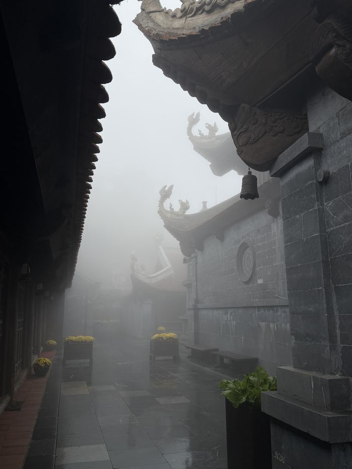 Temple rooftops disappearing into fog on Fansipan